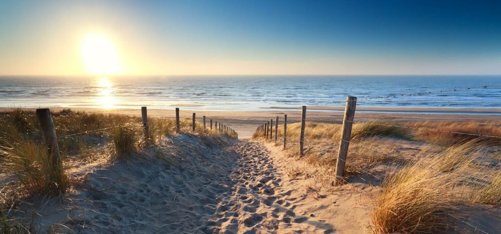 Strand bei Sonnenuntergang mit einem Zaun links und rechts