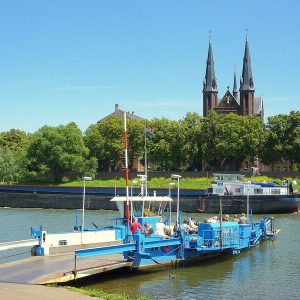 Fähre auf der Maas mit Kirche im Hintergrund